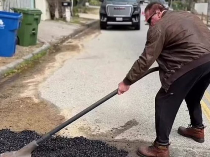 Arnold Schwarzenegger merr një lopatë dhe hedh zhavorr mbi një pellg me ujë në lagjen e tij